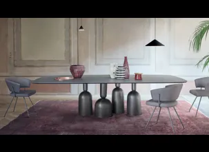 Tavolo Cop con piano in ceramica e base in metallo formata da elementi stilizzati ispirati a bottiglie, calici preziosi e coppe di champagne di Bonaldo